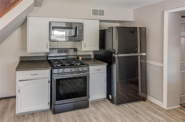 kitchen with stainless steel appliances, dark countertops, and white cabinetry