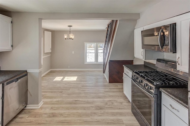 kitchen with stainless steel appliances, light wood finished floors, dark countertops, and white cabinetry