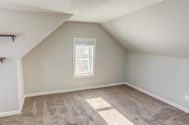 additional living space with carpet floors, lofted ceiling, a textured ceiling, and baseboards