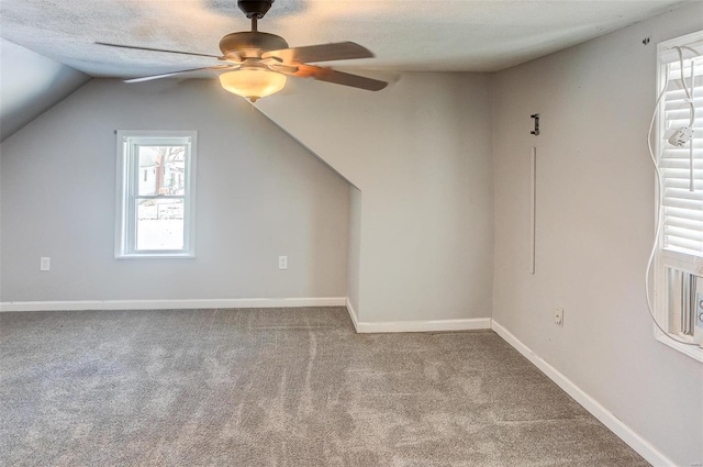 bonus room with ceiling fan, a textured ceiling, light carpet, baseboards, and vaulted ceiling