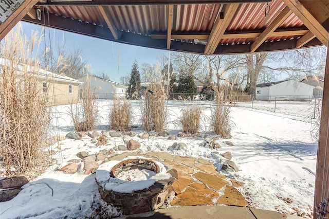 snow covered patio featuring an outdoor fire pit and fence