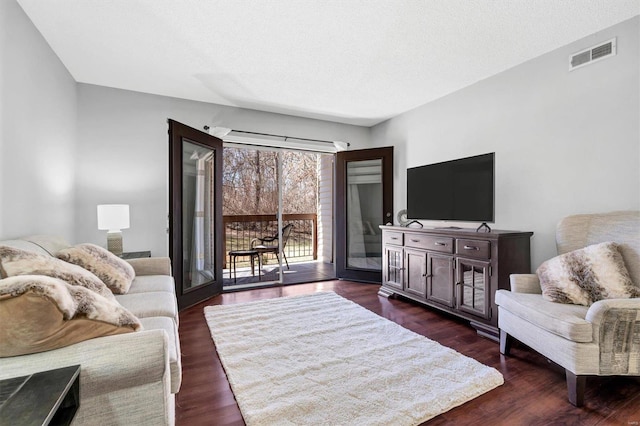 living room with dark wood-style floors, visible vents, and a textured ceiling