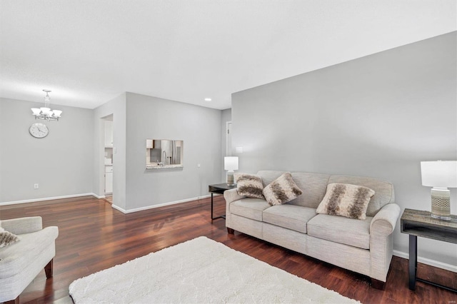 living room featuring an inviting chandelier, baseboards, and wood finished floors