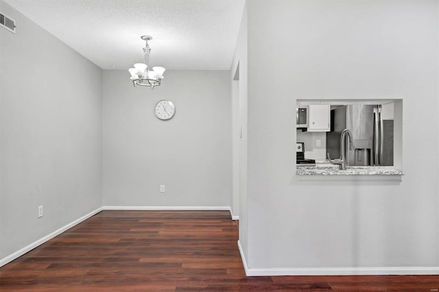 interior space featuring baseboards, visible vents, wood finished floors, a textured ceiling, and a chandelier