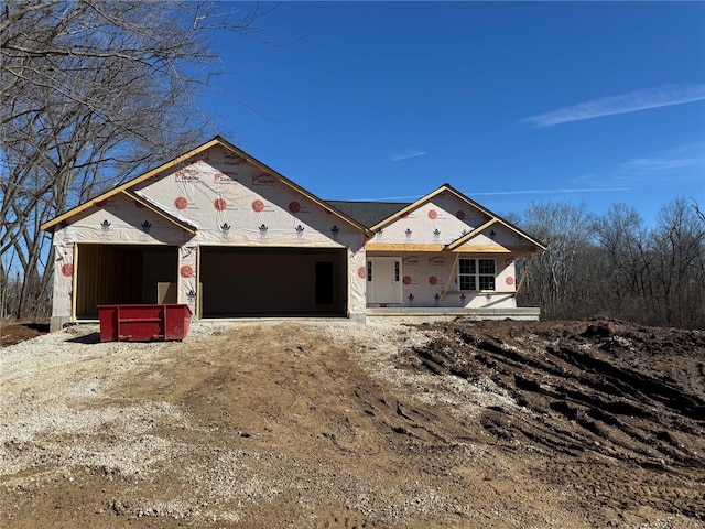 unfinished property with an attached garage and dirt driveway