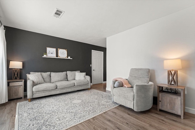 living room with visible vents, baseboards, and wood finished floors