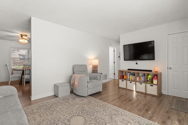 living room featuring a ceiling fan, baseboards, and wood finished floors