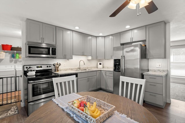 kitchen featuring gray cabinets, washer and clothes dryer, stainless steel appliances, and a sink