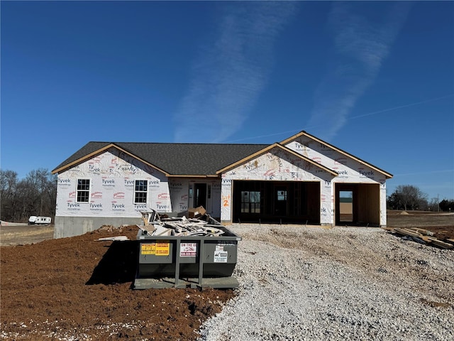 property under construction featuring an attached garage and gravel driveway