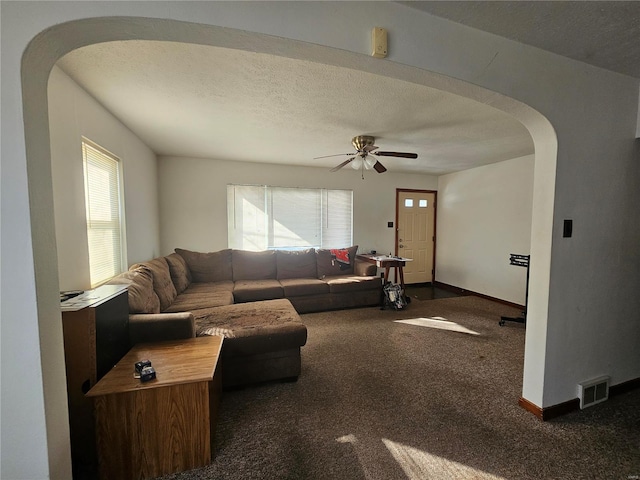 living room featuring baseboards, visible vents, arched walkways, dark colored carpet, and a textured ceiling