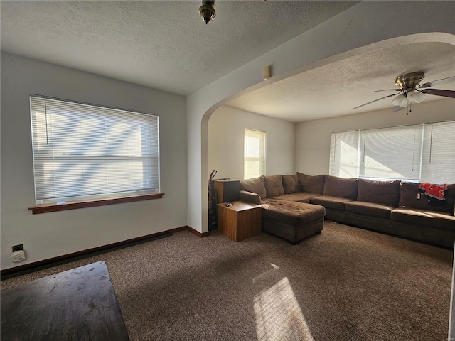 living room with arched walkways, a textured ceiling, carpet flooring, and baseboards