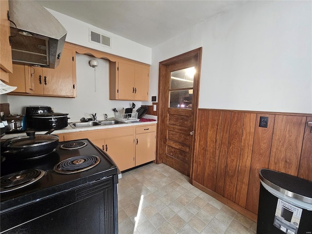 kitchen with black / electric stove, visible vents, light countertops, wainscoting, and range hood