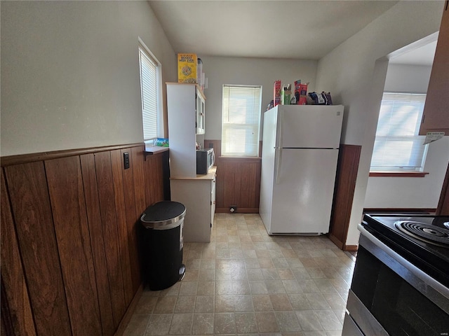 kitchen featuring appliances with stainless steel finishes, wainscoting, plenty of natural light, and wood walls