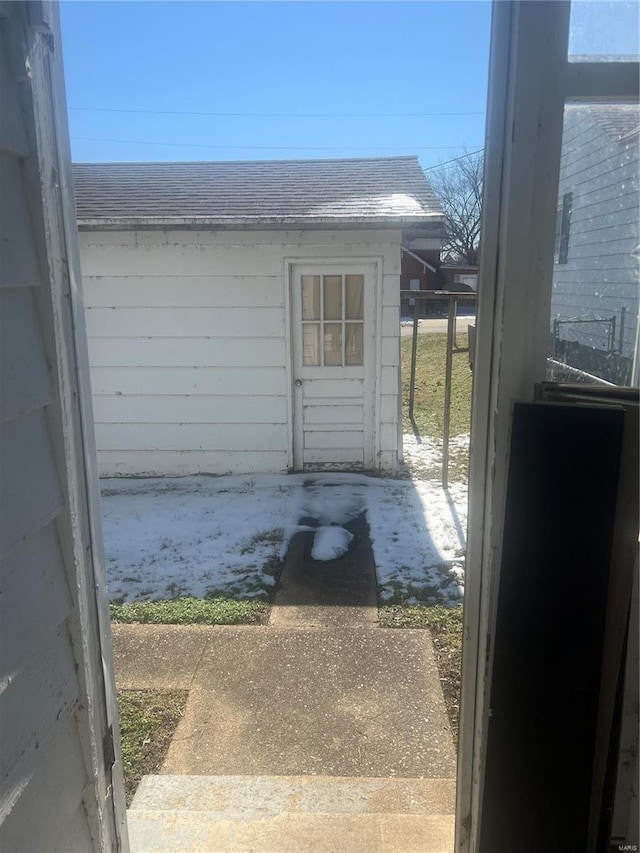 view of exterior entry with roof with shingles