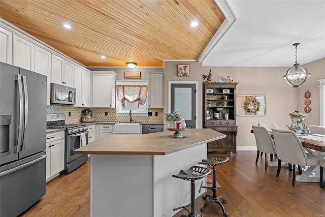 kitchen featuring a sink, tasteful backsplash, wood finished floors, appliances with stainless steel finishes, and wooden ceiling