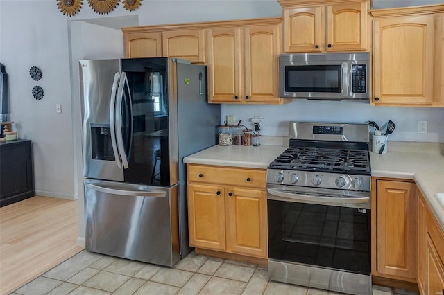 kitchen featuring stainless steel appliances, light countertops, and baseboards