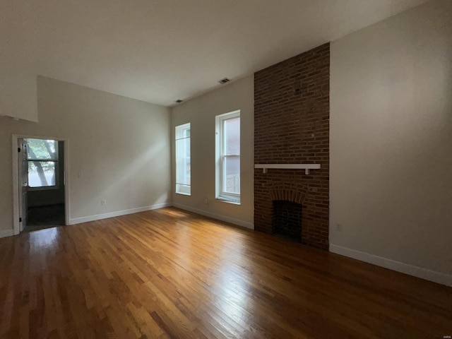 unfurnished living room with vaulted ceiling, a fireplace, wood finished floors, and baseboards