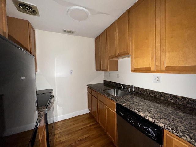 kitchen with visible vents, dark wood finished floors, dark stone counters, stainless steel appliances, and a sink