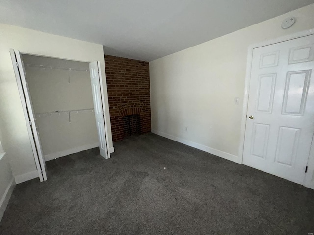 unfurnished bedroom featuring a closet, a fireplace, dark carpet, and baseboards