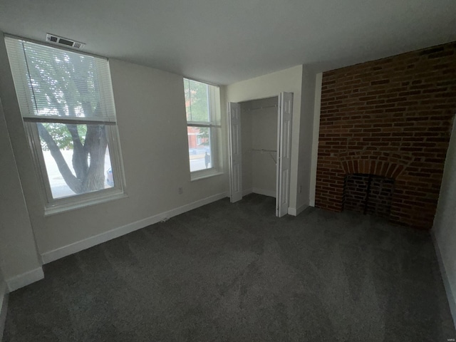 unfurnished bedroom with baseboards, visible vents, dark carpet, and a fireplace