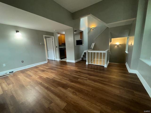 unfurnished living room with dark wood-style floors, stairs, and baseboards