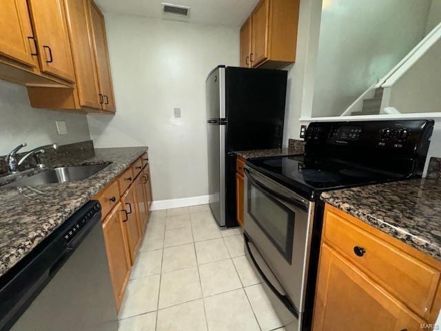 kitchen featuring stainless steel appliances, visible vents, brown cabinetry, light tile patterned flooring, and a sink