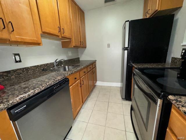 kitchen with stainless steel appliances, brown cabinetry, a sink, and light tile patterned flooring