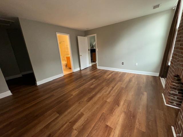 unfurnished bedroom featuring connected bathroom, dark wood finished floors, visible vents, and baseboards