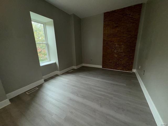 spare room with baseboards, visible vents, and wood finished floors