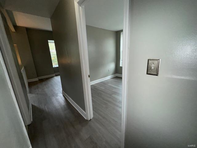 hallway featuring dark wood-style flooring and baseboards