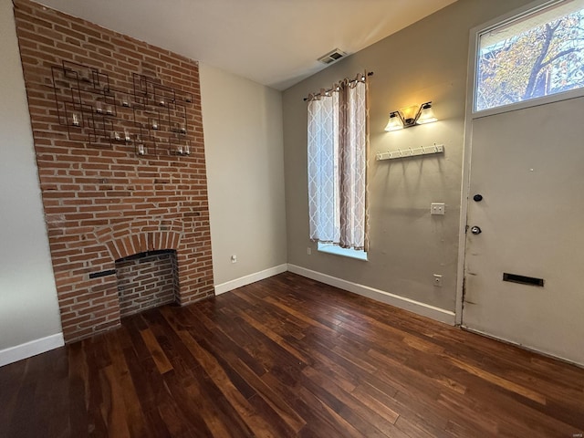 unfurnished living room with baseboards, a fireplace, visible vents, and wood finished floors