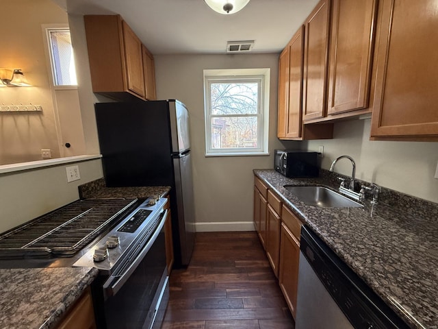 kitchen featuring dark wood finished floors, visible vents, appliances with stainless steel finishes, a sink, and baseboards