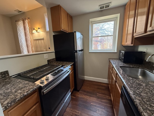 kitchen featuring dark wood-type flooring, a sink, visible vents, baseboards, and appliances with stainless steel finishes