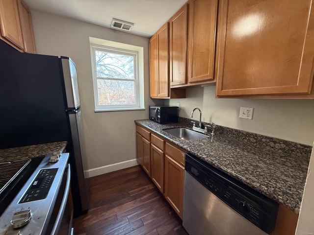 kitchen featuring baseboards, visible vents, appliances with stainless steel finishes, dark wood-style flooring, and a sink