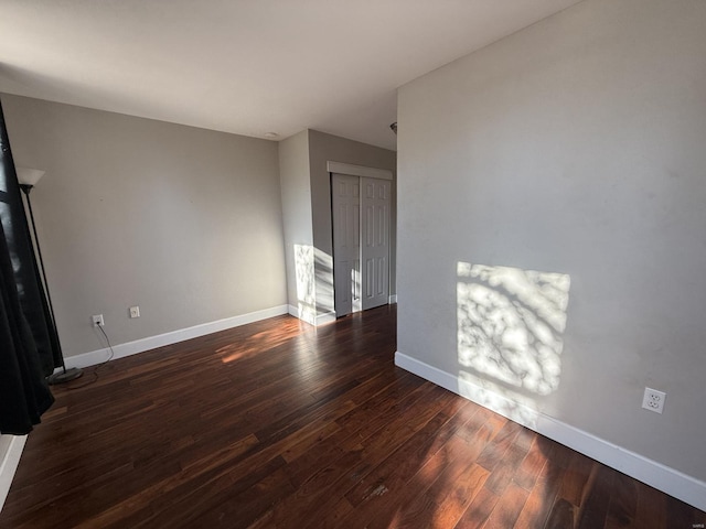 unfurnished living room featuring hardwood / wood-style flooring and baseboards