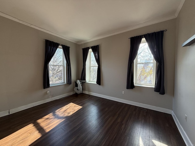 unfurnished room with visible vents, crown molding, baseboards, and wood finished floors