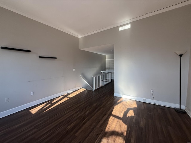 spare room featuring baseboards, wood finished floors, and crown molding