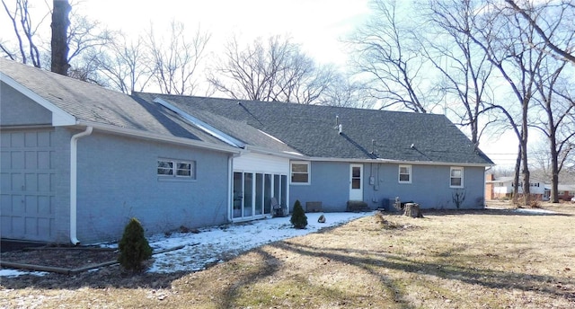 rear view of house with a yard, roof with shingles, and brick siding