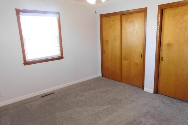 unfurnished bedroom featuring baseboards, visible vents, light colored carpet, crown molding, and a closet