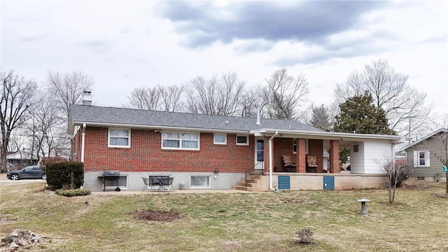 view of front of home with brick siding, a chimney, a front yard, and a shingled roof