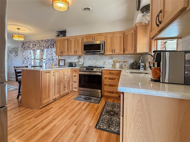 kitchen featuring light wood finished floors, visible vents, decorative backsplash, appliances with stainless steel finishes, and a sink