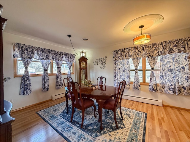 dining area with a baseboard radiator, visible vents, and wood finished floors