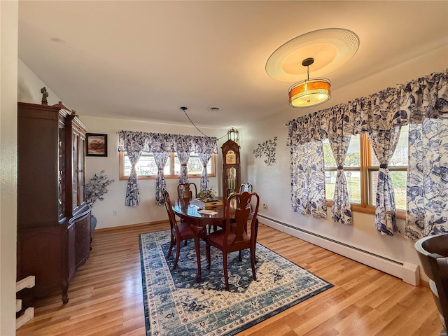 dining area with a baseboard radiator, baseboards, and light wood-style flooring