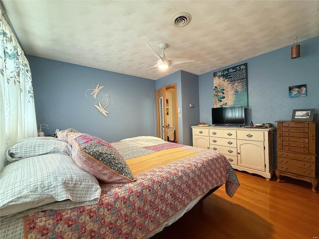 bedroom with visible vents, ceiling fan, a textured ceiling, and wood finished floors