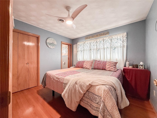 bedroom with ceiling fan, wood finished floors, and visible vents