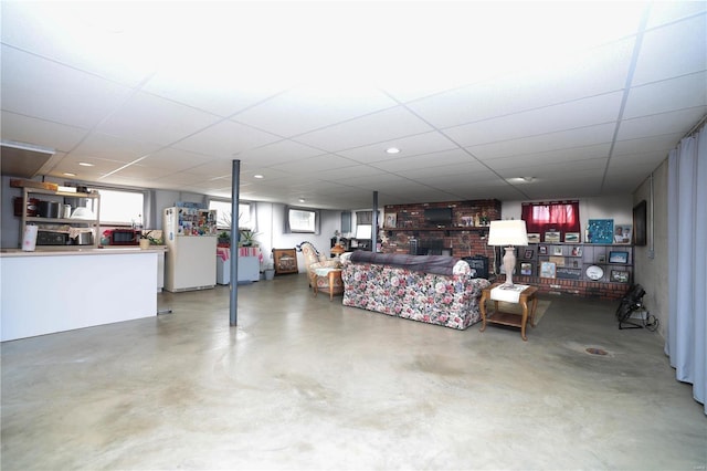 living area with a paneled ceiling and finished concrete flooring