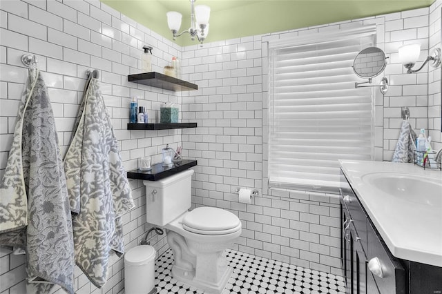 bathroom featuring tile patterned flooring, toilet, vanity, tile walls, and an inviting chandelier