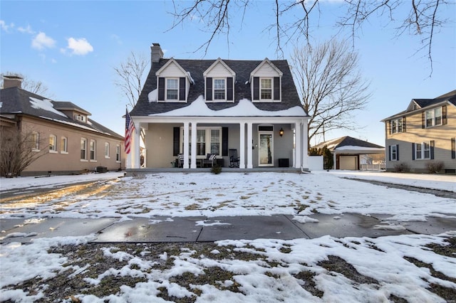 view of front of property featuring a porch, a detached garage, and a chimney