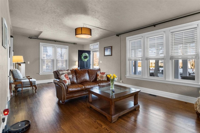 living area with a textured ceiling, dark wood finished floors, and baseboards