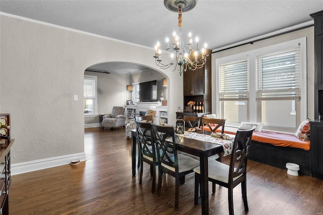 dining room featuring dark wood-style floors, a textured wall, arched walkways, and crown molding